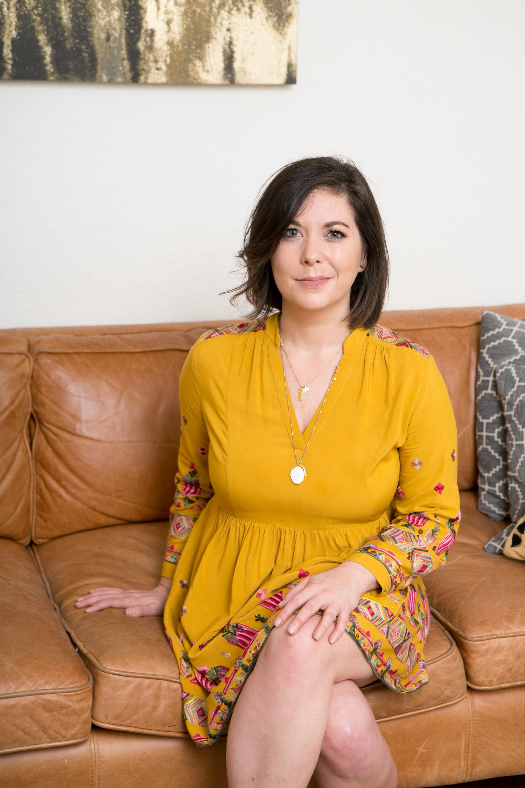 Michelle Harwell in a yellow dress sitting on a leather couch
